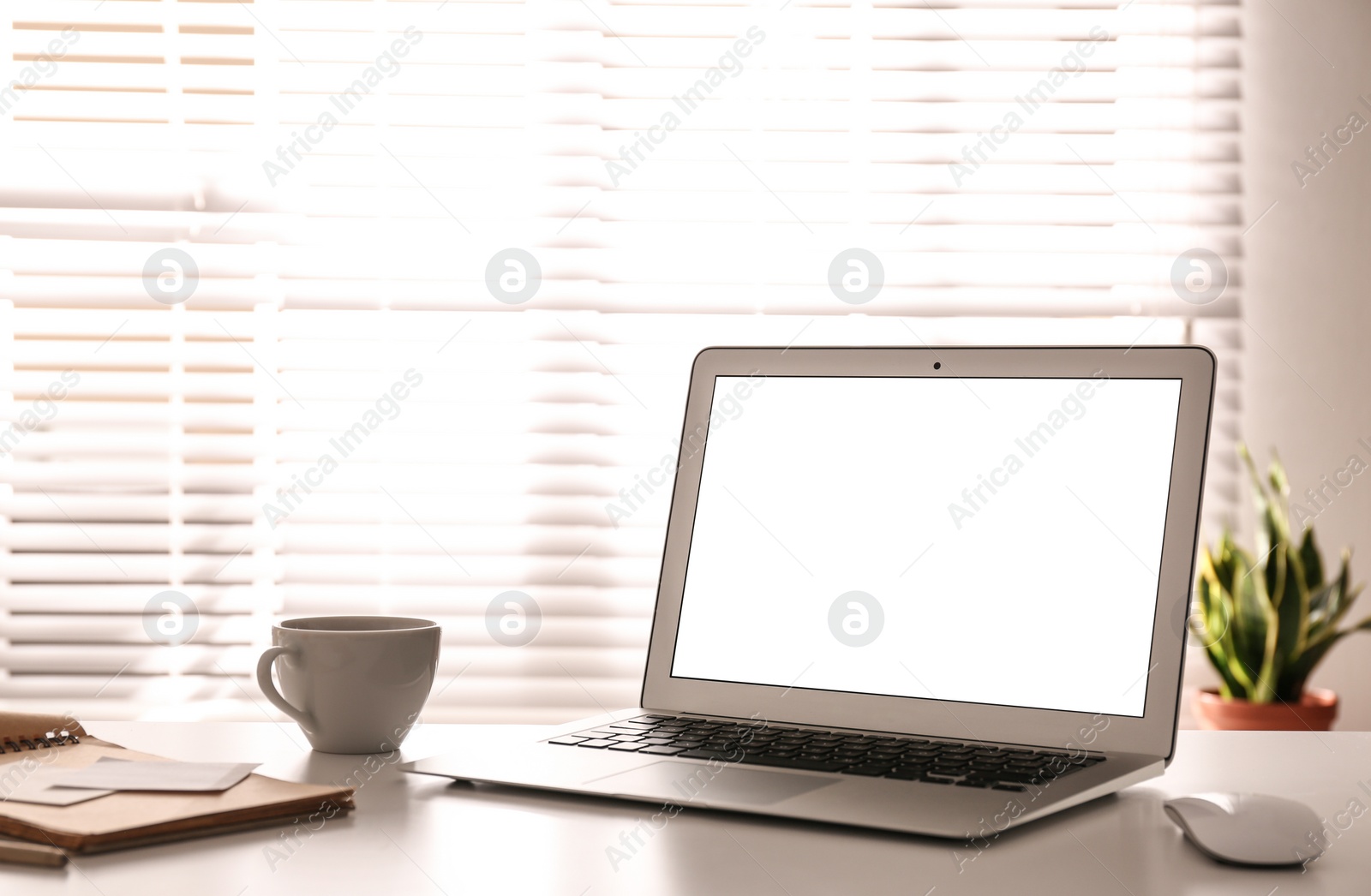 Photo of Laptop on desk near window in office. Comfortable workplace