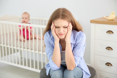 Photo of Young mother suffering from postnatal depression and little baby in room