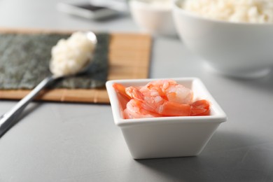 Photo of Shrimps in bowl for sushi on grey textured table, closeup