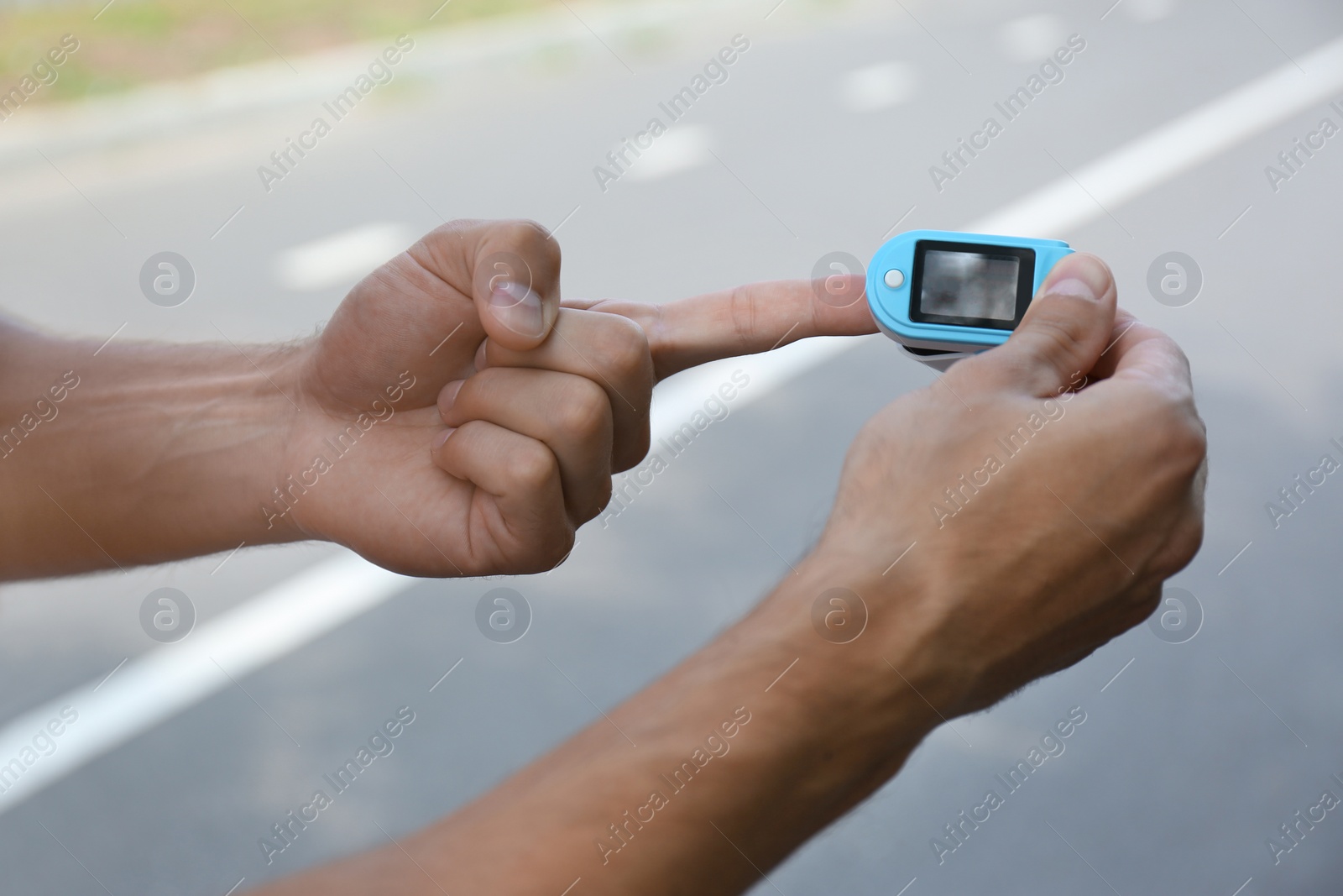 Photo of Young man checking pulse with medical device after training, closeup