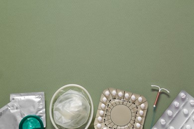 Photo of Contraceptive pills, condoms and intrauterine device on olive background, flat lay with space for text. Different birth control methods