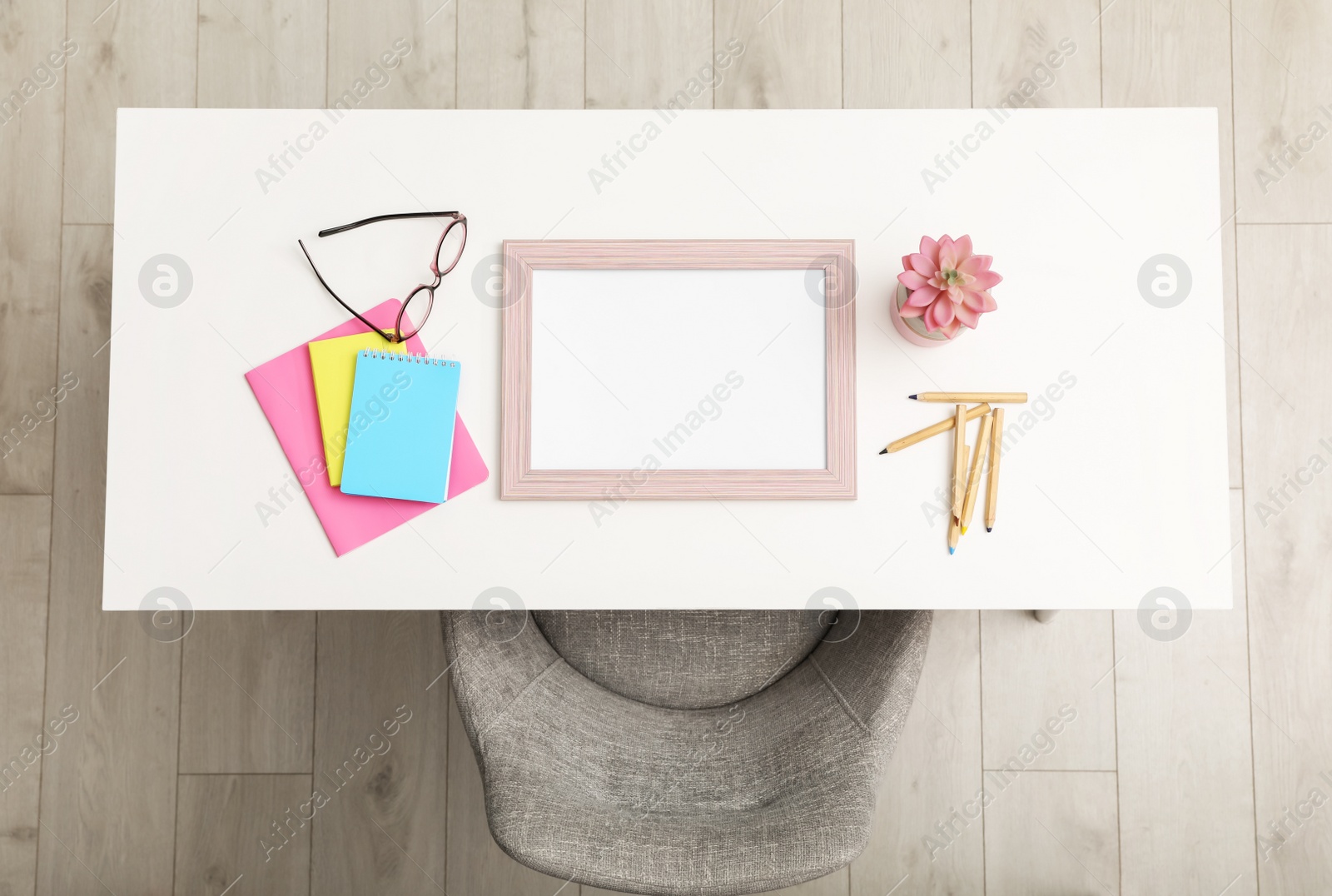 Photo of Empty frame and stationery on white table indoors, top view