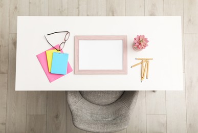 Empty frame and stationery on white table indoors, top view