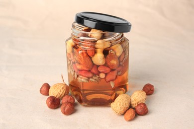 Photo of Jar with different nuts and honey on beige background