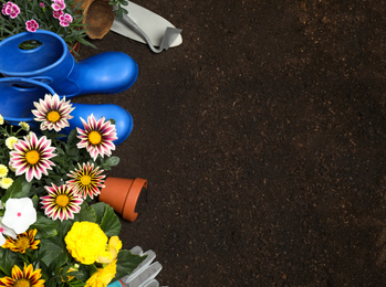 Photo of Flat lay composition with gardening tools and flowers on soil, space for text