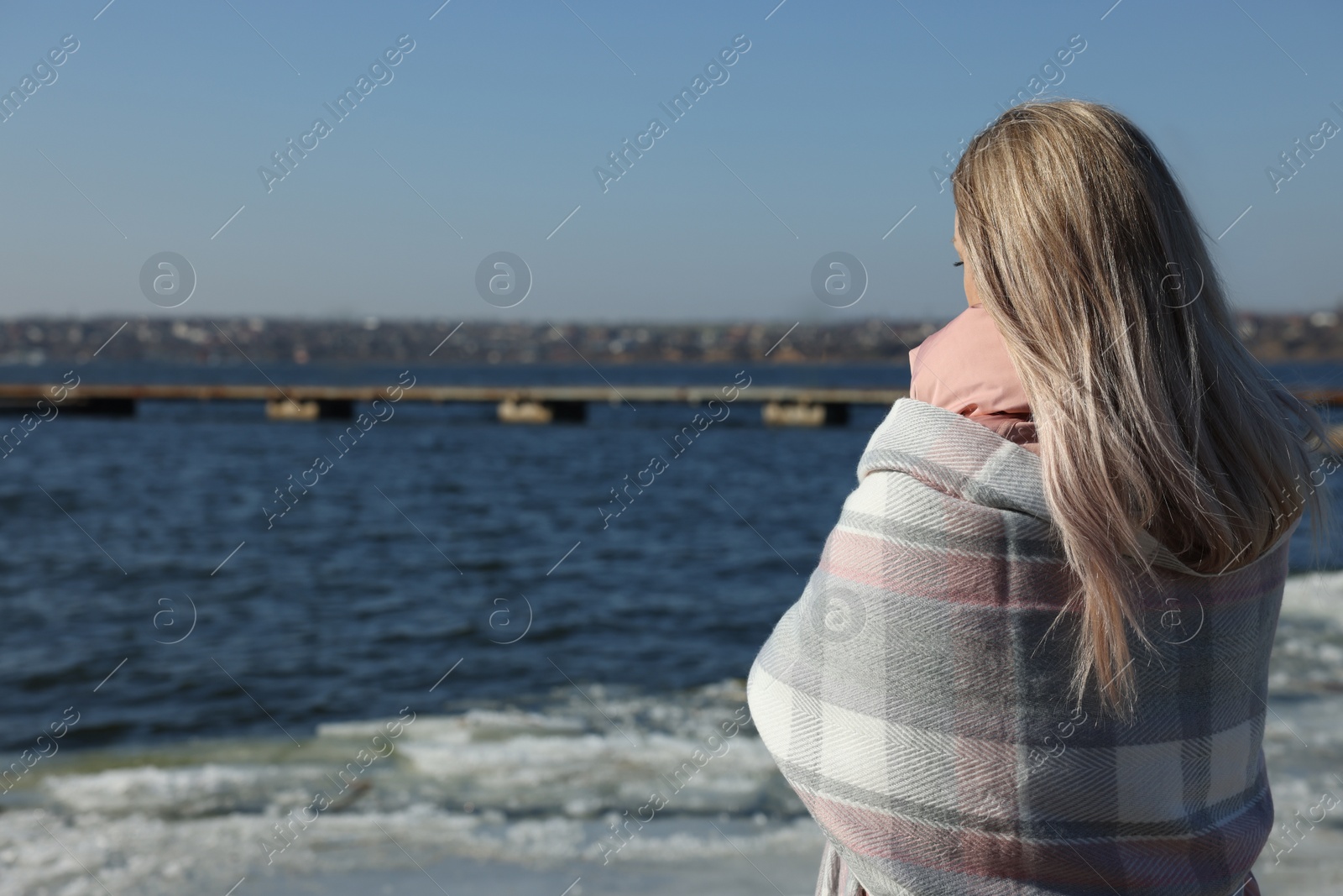 Photo of Lonely woman near river on sunny day, back view