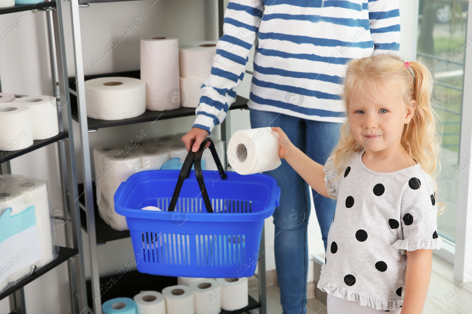 Photo of Young mother and little girl choosing toilet paper in shop