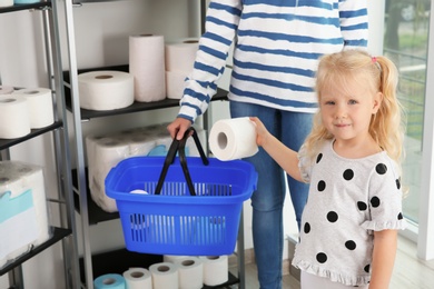 Young mother and little girl choosing toilet paper in shop