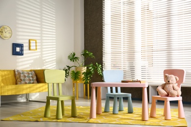 Photo of Stylish playroom interior with table, chairs and sofa