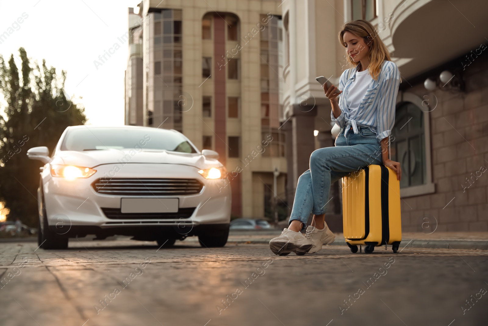 Photo of Woman ordering taxi with smartphone on city street