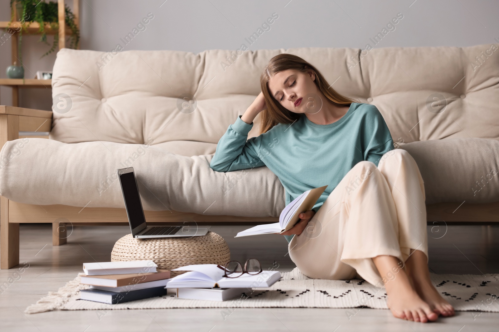 Photo of Young tired woman sleeping near couch at home