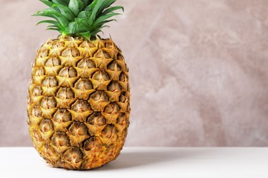 Delicious ripe pineapple on white table near pink wall, closeup. Space for text