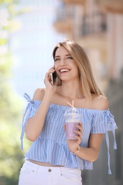 Young woman with plastic cup of healthy smoothie outdoors