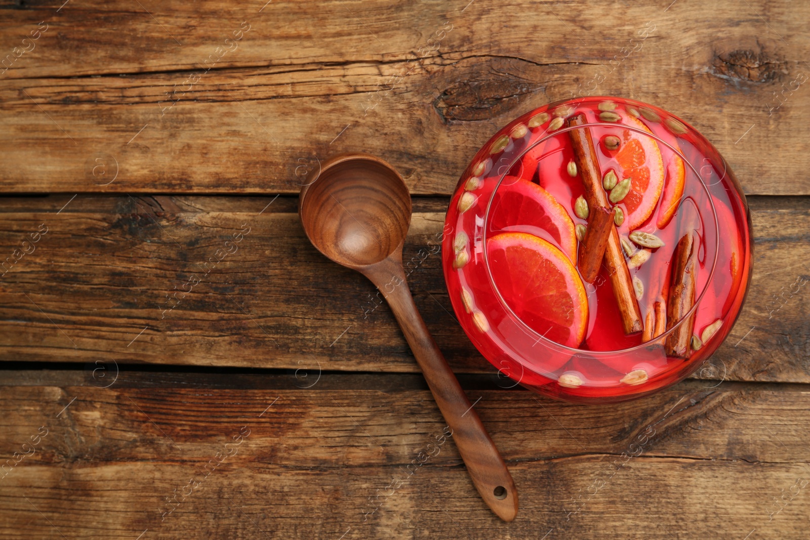 Photo of Glass bowl of aromatic punch drink and ladle on wooden table, flat lay. Space for text