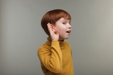 Photo of Little boy with hearing problem on grey background
