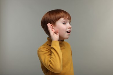 Little boy with hearing problem on grey background