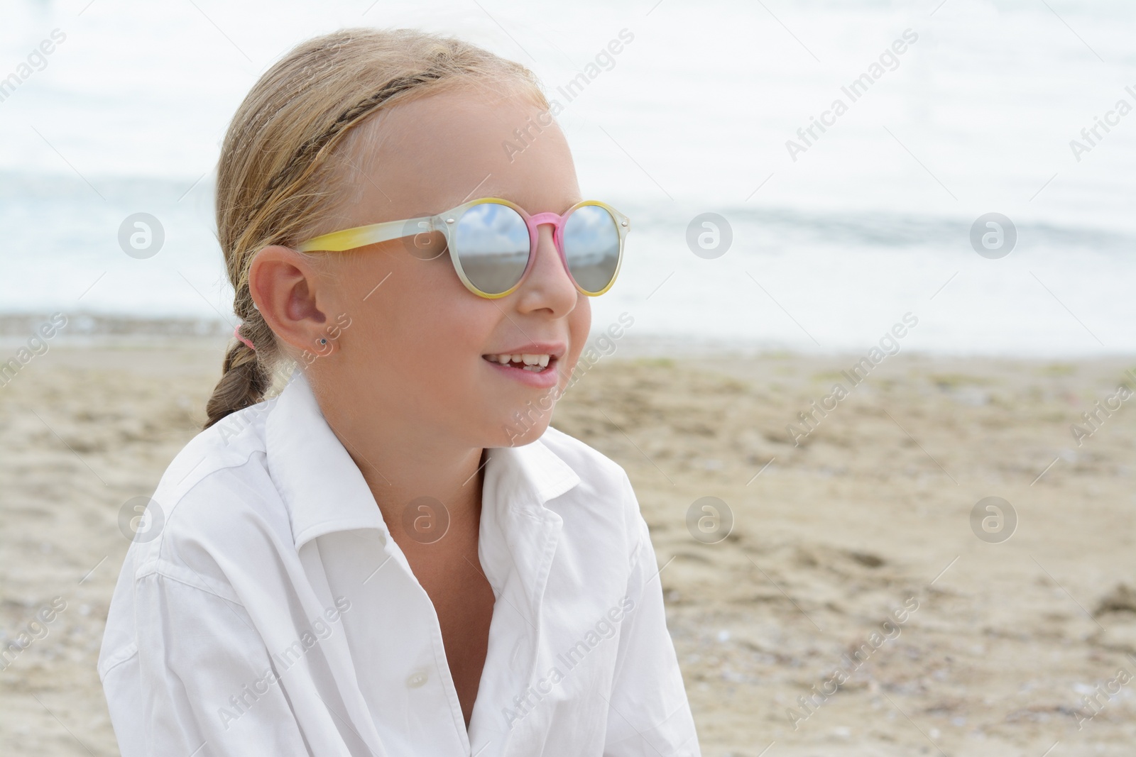 Photo of Little girl wearing sunglasses at beach on sunny day. Space for text