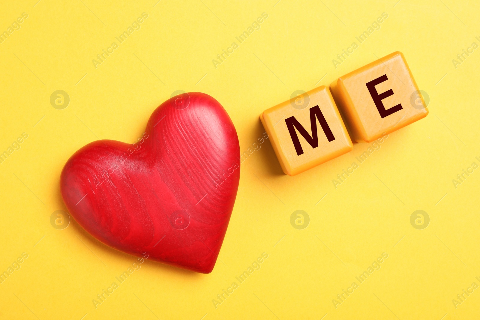 Photo of Phrase Love Me made with cubes and heart on yellow background, flat lay