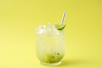 Photo of Glass of refreshing drink with kiwi and lime on yellow background