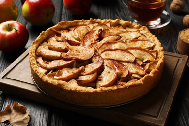 Photo of Delicious apple pie on black wooden table