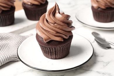 Photo of Delicious fresh chocolate cupcake on white marble table, closeup