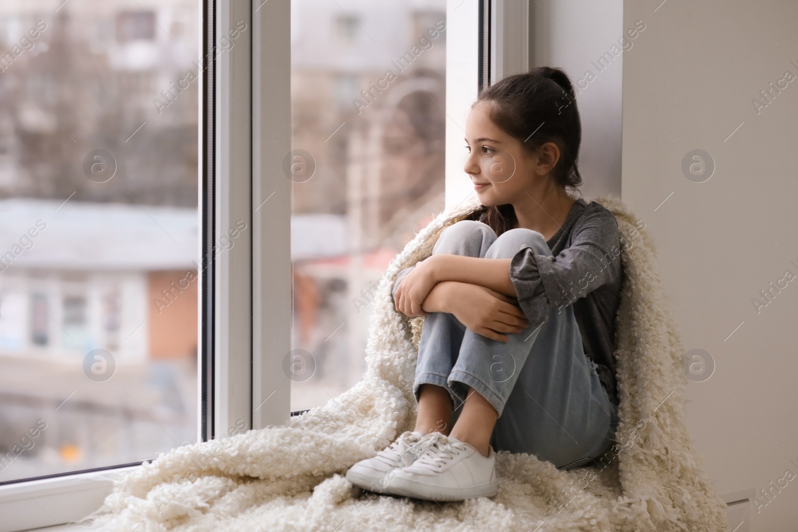 Photo of Cute little girl resting near window at home. Space for text