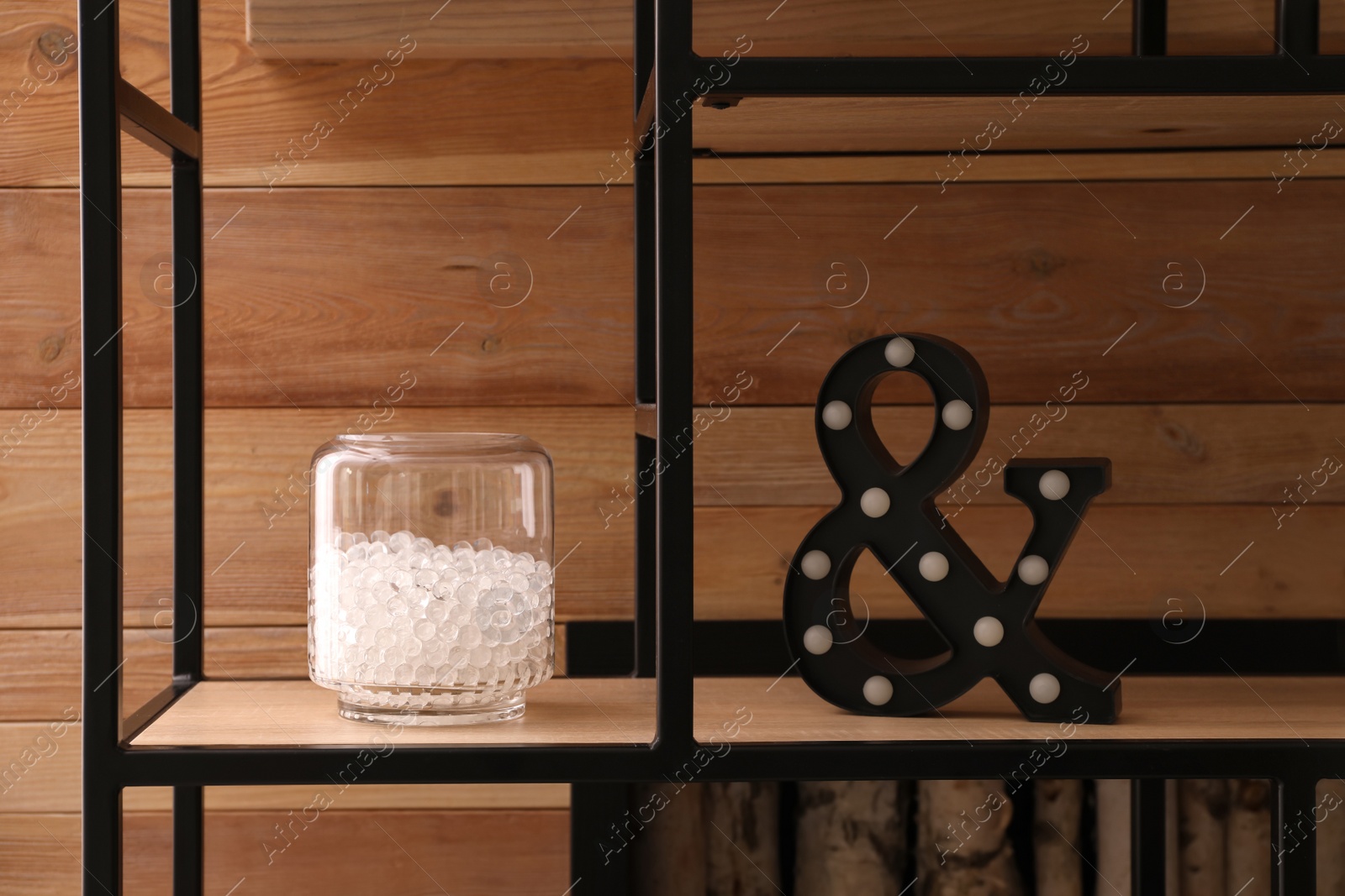 Photo of White filler in glass vase on shelf against wooden wall. Water beads