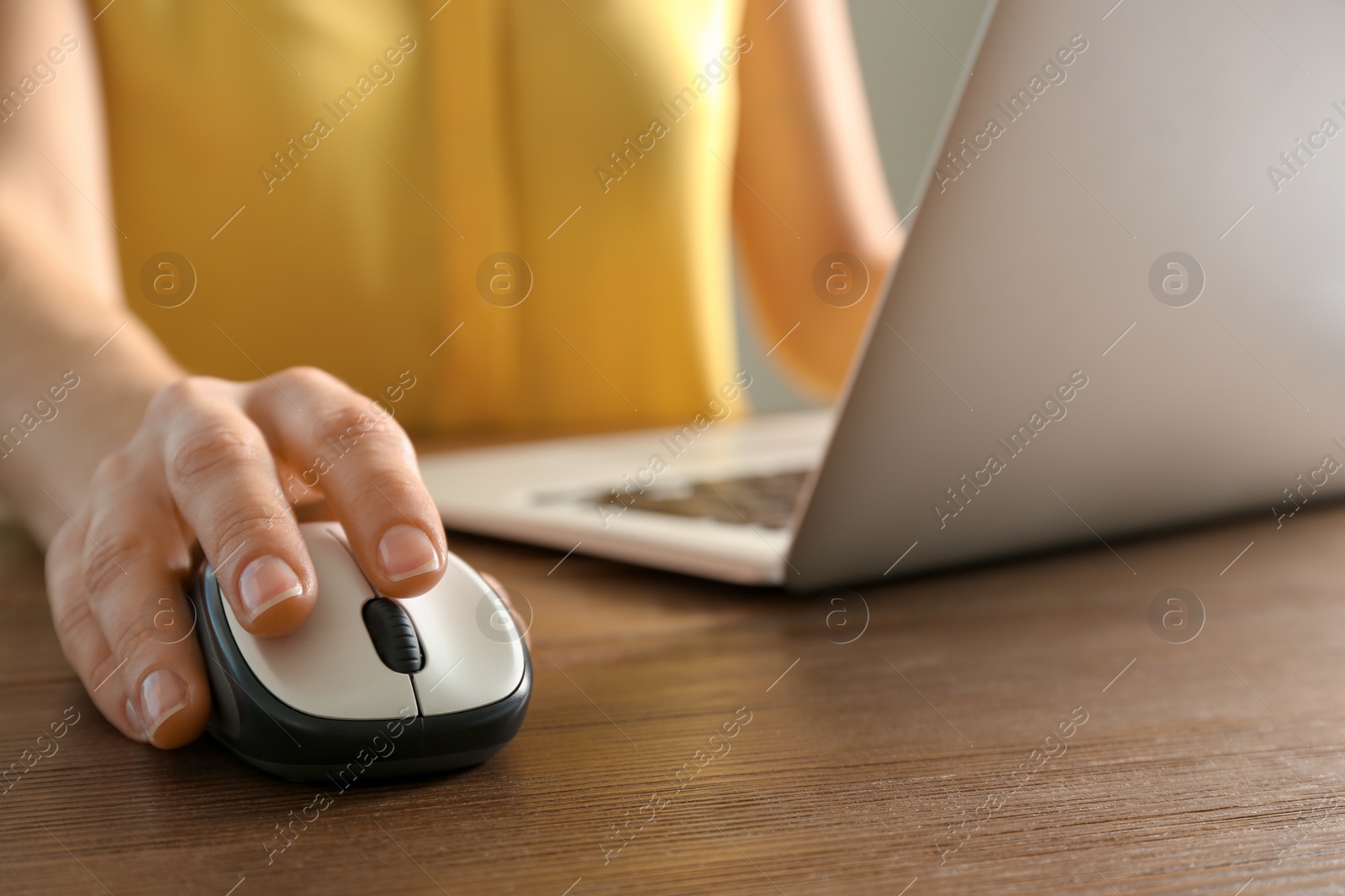 Photo of Woman using computer mouse with laptop at table, closeup