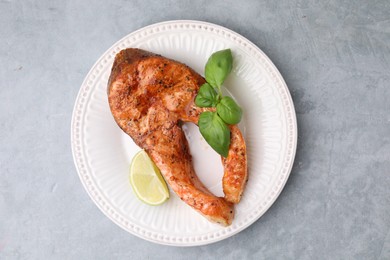 Freshly cooked fish, lime and basil on grey table, top view