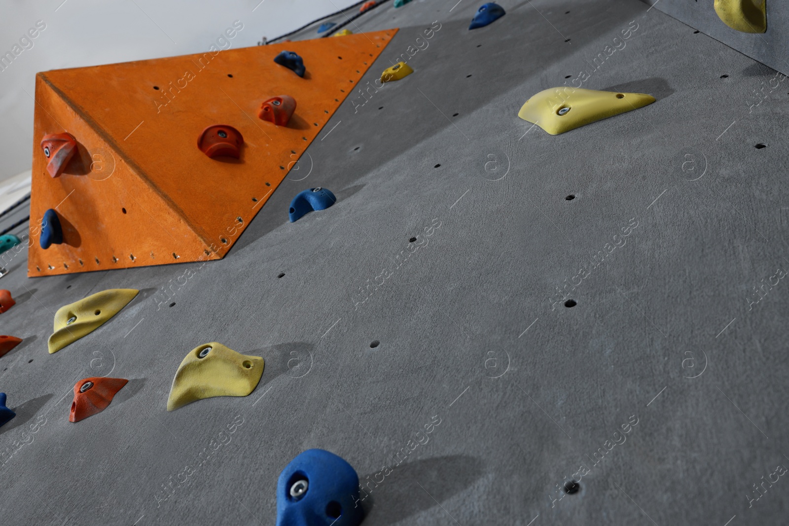 Photo of Climbing wall with holds in gym, low angle view. Extreme sport