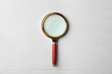 Photo of Magnifier glass on white wooden background, top view. Find keywords concept