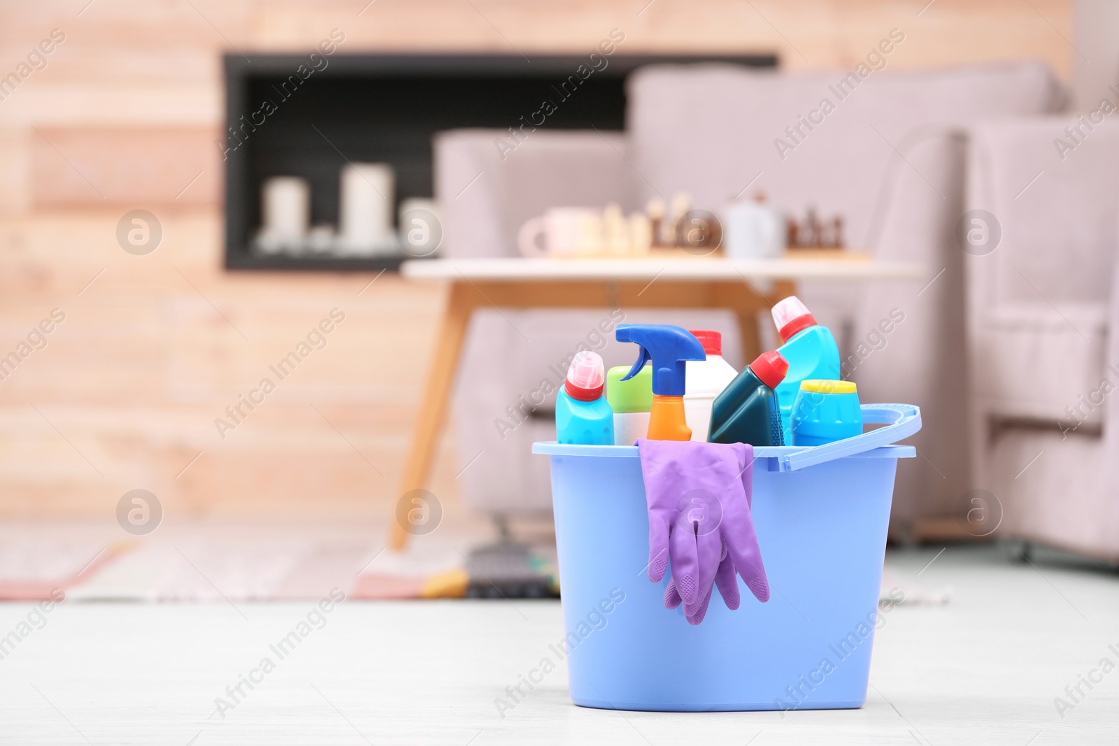 Photo of Bucket with cleaning supplies on floor indoors. Space for text