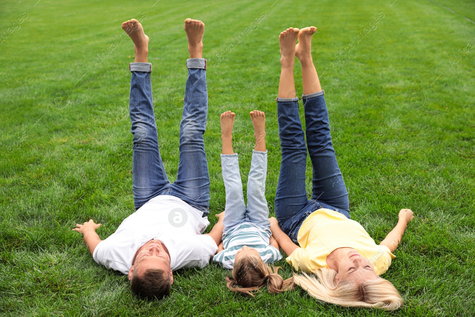 Photo of Happy family lying on green grass in park