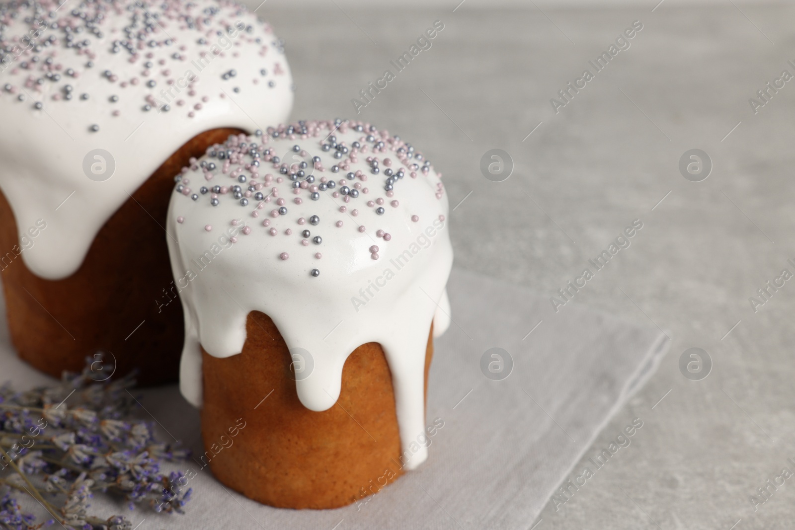 Photo of Tasty Easter cakes and lavender flowers on grey table. Space for text