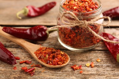 Photo of Chili pepper flakes and pods on wooden table, closeup