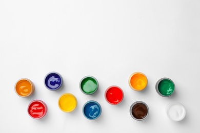 Photo of Different paints in jars on white background, top view. Color palette