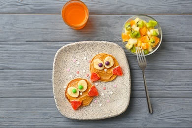 Flat lay composition with pancakes in form of owls on wooden background. Creative breakfast ideas for kids