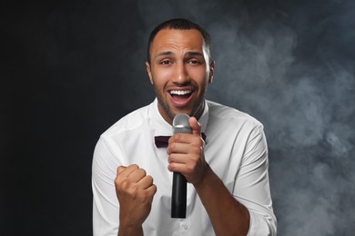 Handsome man with microphone singing on black background