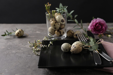 Festive Easter table setting with quail eggs and floral decoration on dark background