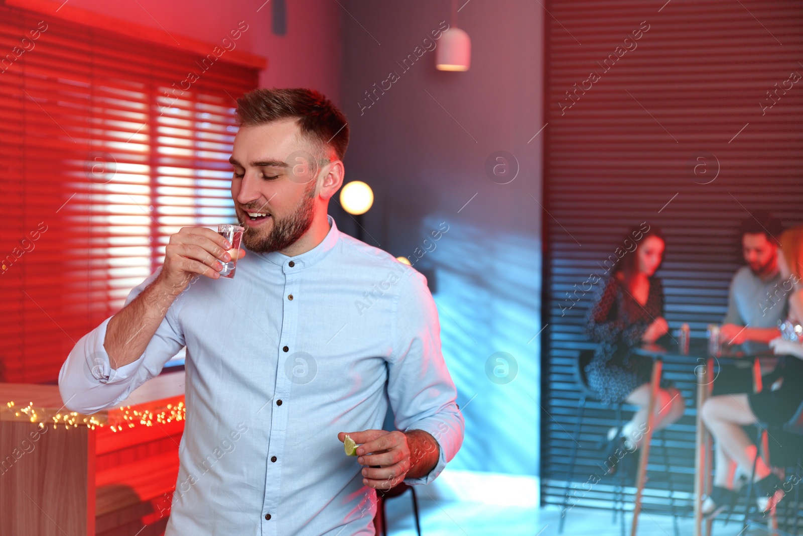 Photo of Young man with Mexican Tequila shot in bar. Space for text