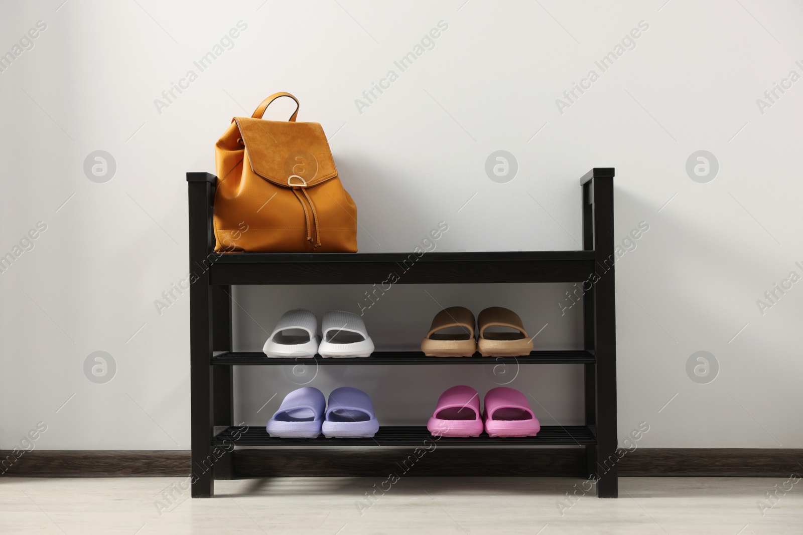 Photo of Storage bench with pairs of rubber slippers indoors