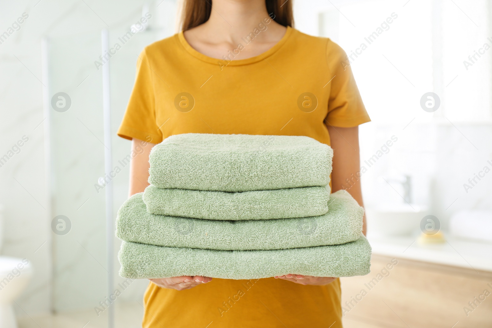 Photo of Woman holding fresh towels in bathroom, closeup