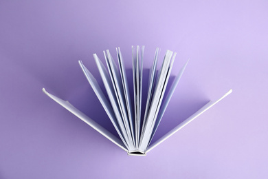 Photo of Hardcover book on violet background, top view