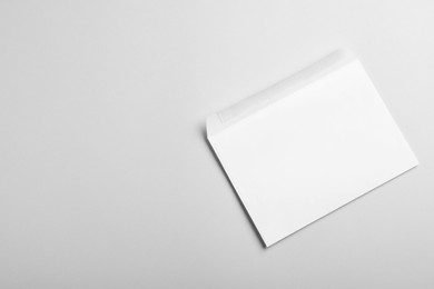 Photo of White paper envelope on light grey background, top view. Space for text
