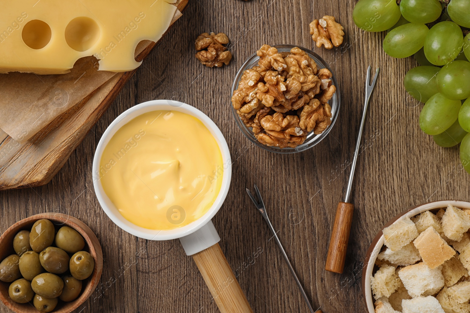 Photo of Flat lay composition with pot of tasty cheese fondue on wooden table