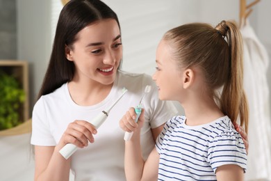 Photo of Mother and her daughter brushing teeth together in bathroom