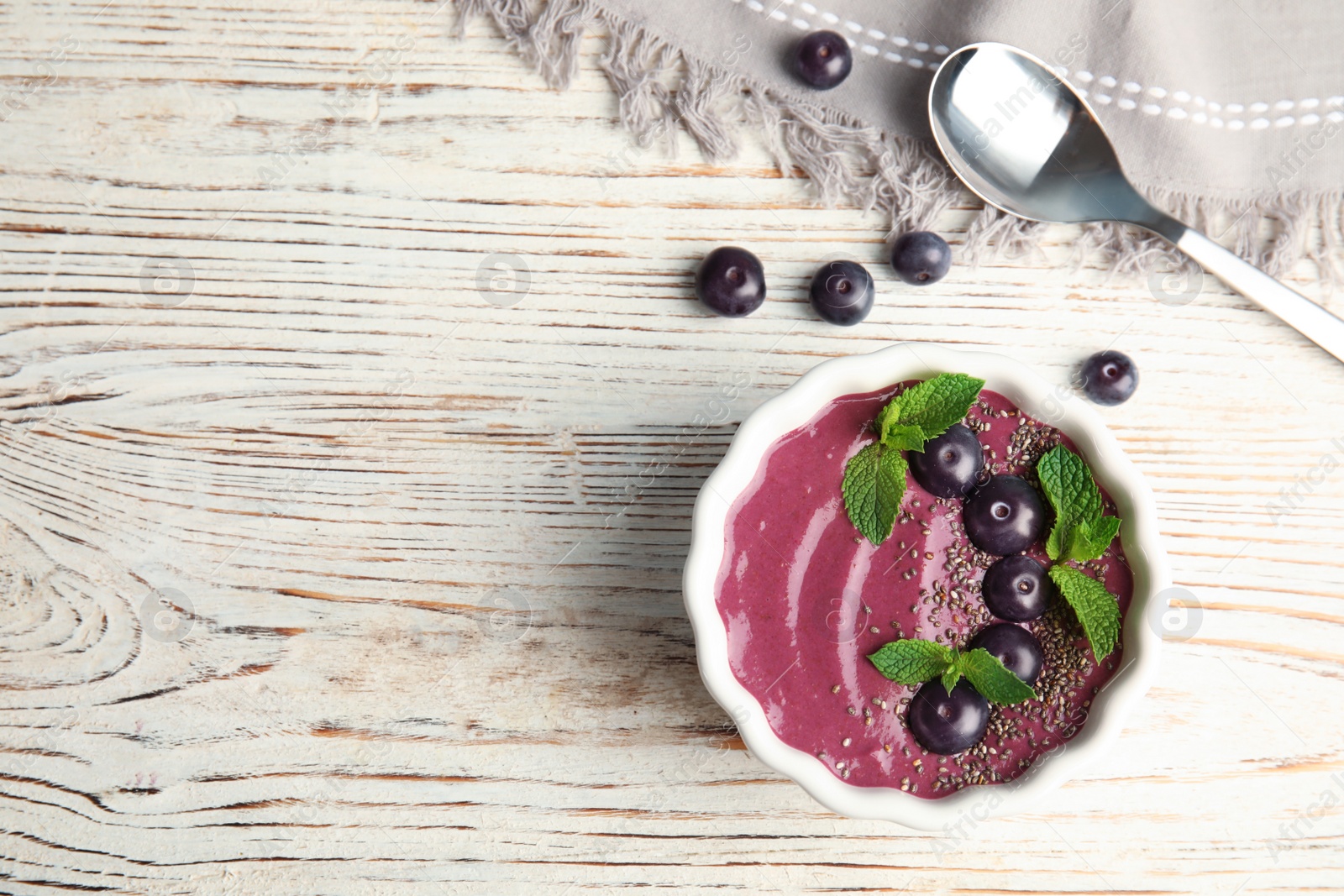 Photo of Flat lay composition with bowl of tasty acai smoothie on wooden table