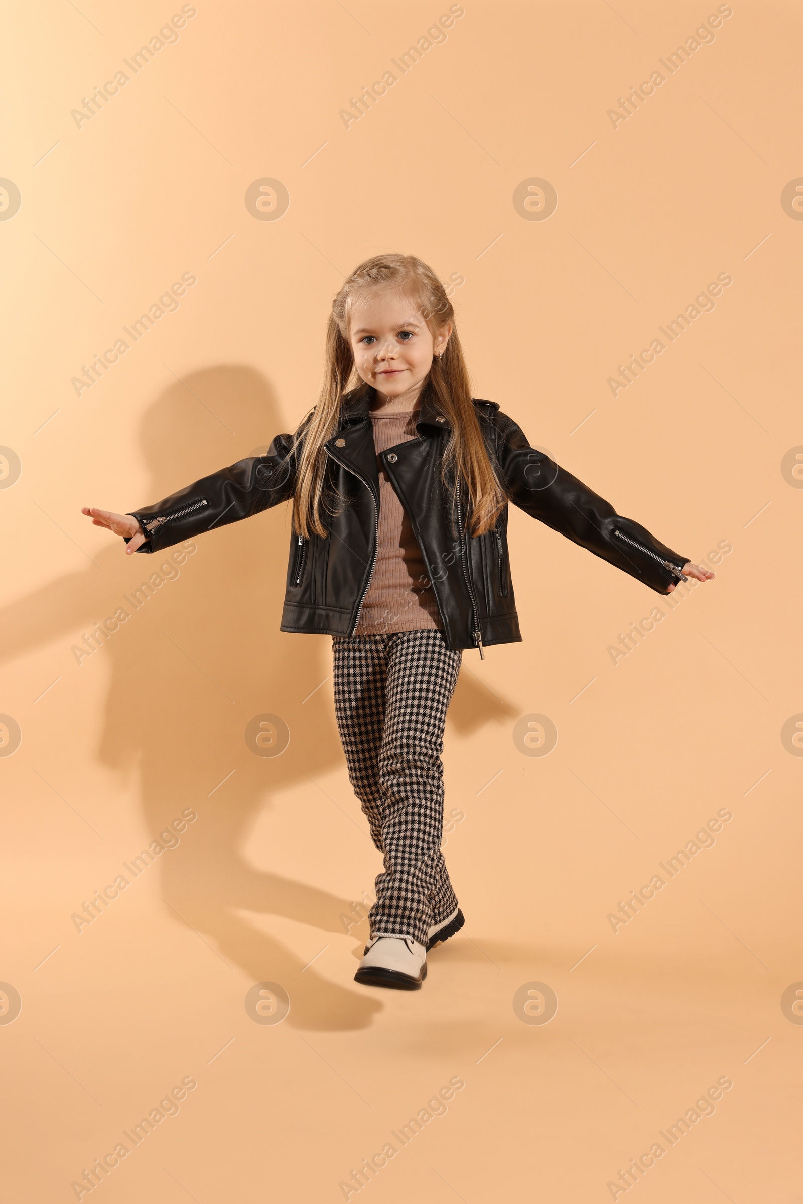 Photo of Fashion concept. Stylish girl posing on pale orange background