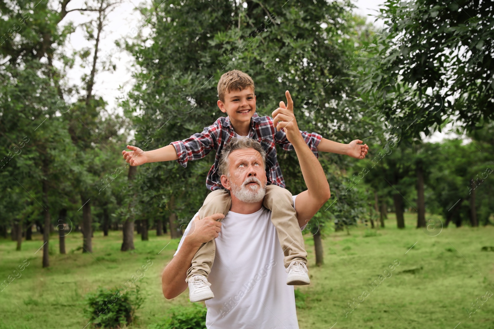 Photo of Cute little boy and grandfather spending time together in park