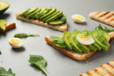 Photo of Tasty avocado toasts on light grey table